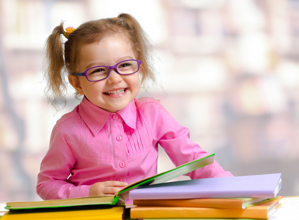 happy little girl with glasses reading books