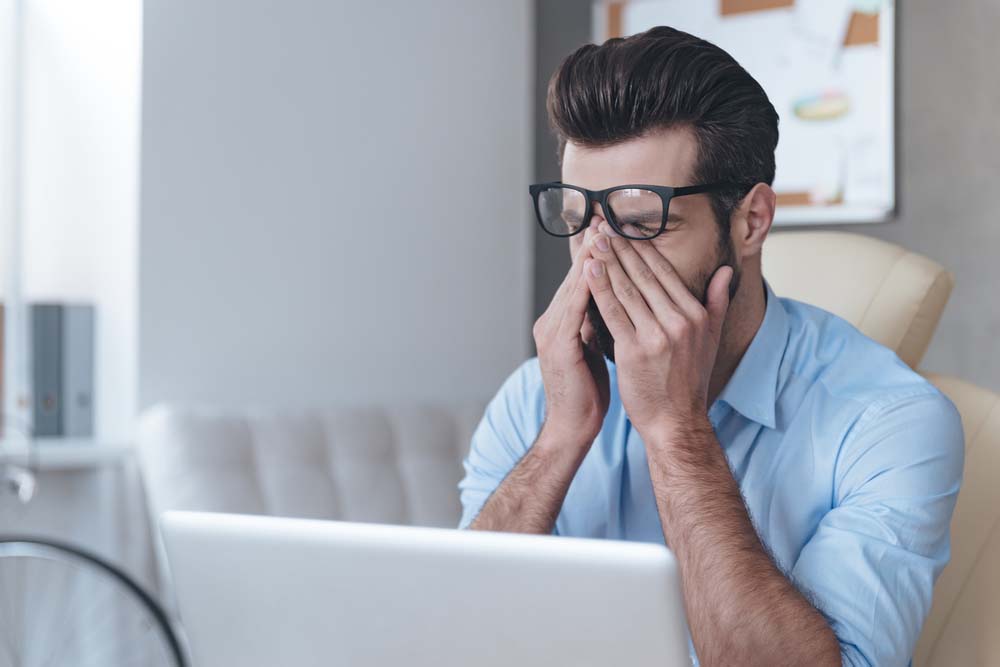 Man struggling with his eye site on his laptop.