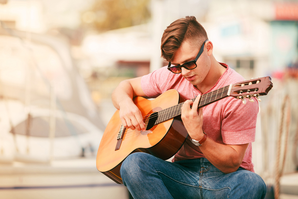 Man with Dolce and Gabbana sunglasses playing guitar