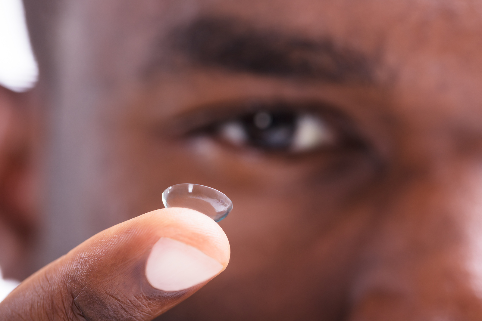 man with a contact lens on his fingertip