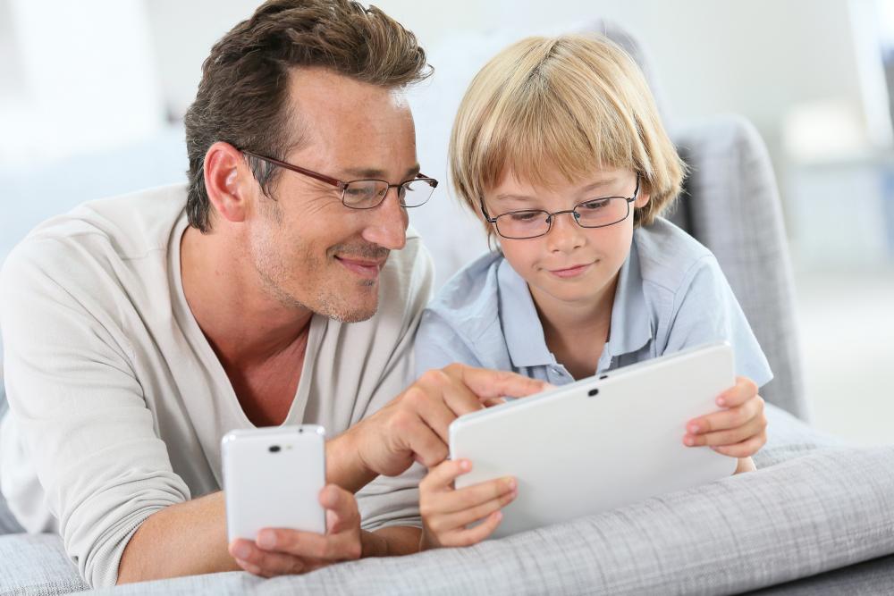father and son looking at their tablet and phone