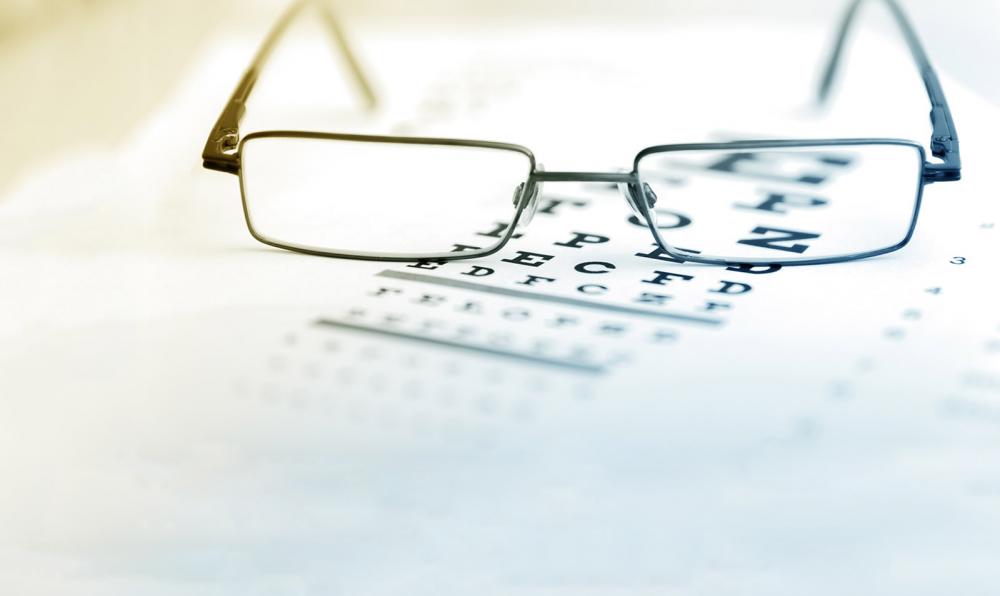 A pair of glasses sitting on a eye exam chart.