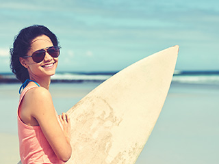 A Lady At The Beach Holding A Surf Board - Sunglasses Pensacola - Fifty Dollar Eye Guy 5328 N Davis Hwy Pensacola, FL 32503 (850) 434-6387