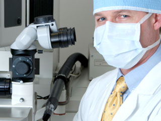 A Male Eye Doctor With A Microscope and Medical Mask- Lasik Eye Surgery Pensacola- Fifty Dollar Eye Guy 5328 N Davis Hwy Pensacola, FL 32503 (850) 434-6387