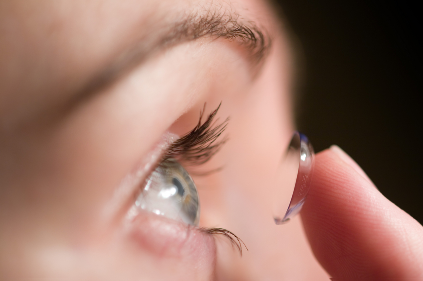 woman putting in contact lens in her eyes